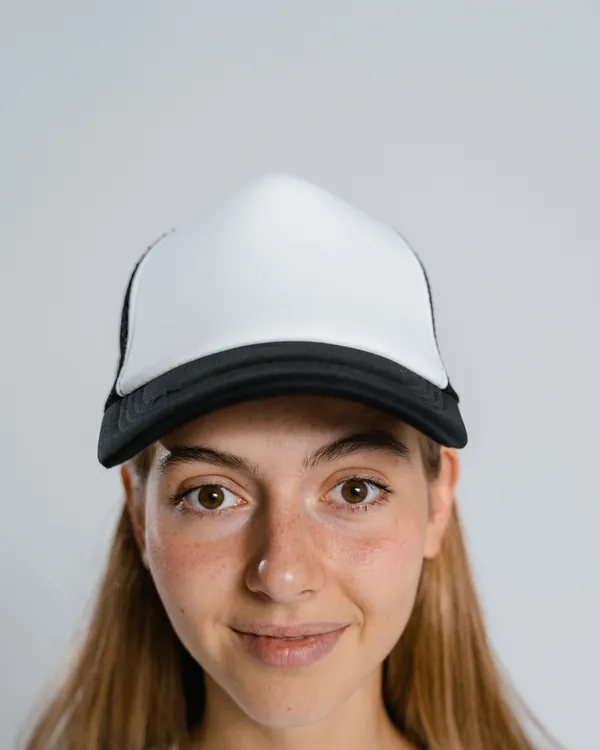Woman wearing a trucker cap with a white front and black brim, against a light grey background